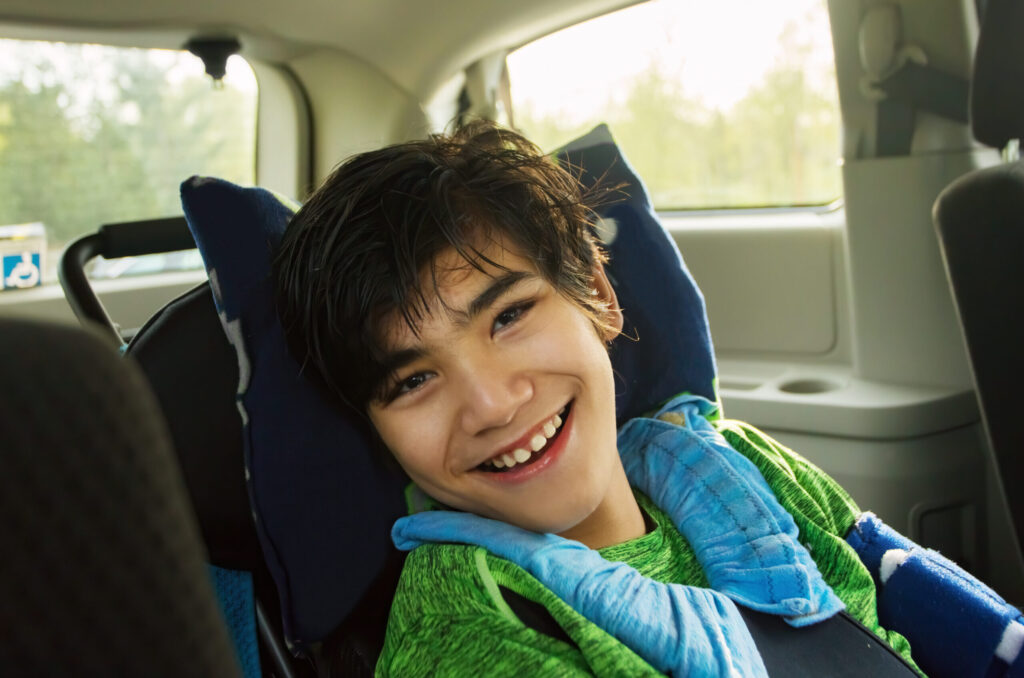 Smiling twelve year old biracial disabled boy in handicap vehicle sitting in wheelchair