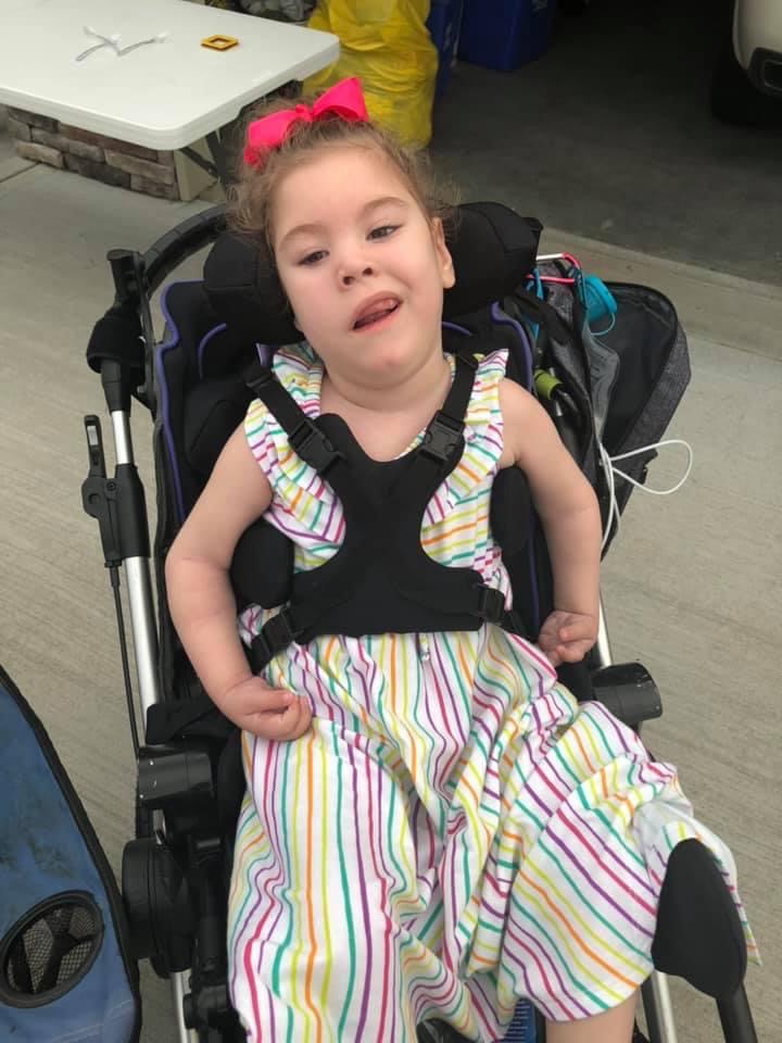 young girl in wheelchair wearing a colorful striped sun dress